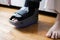 women broken feet with a grey plastic boot ankle brace injury protecting boot