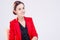 Women in Business Ideas. Portrait of Caucasian Brunette Enterpreneur in Red Blazer Posing in Chair Against White