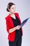 Women in Business Ideas. Portrait of Caucasian Brunette Enterpreneur in Red Blazer Posing With Paper Folder Notebook Against White