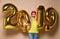 Women celebrating New Year party happy laughing in yellow sweater blouse with 2019 gold balloons