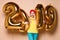 Women celebrating New Year xmas party happy laughing in yellow sweater blouse with 2019 gold balloons