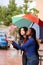 Women checking weather while standing on the street under an umbrella in a rainy day.