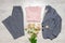 Women classic suit in grey color with pink pastel accessories and bouquets on light background. Jacket and trousers with