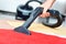 Women cleaning a red carpet with a black vacuum cleaner