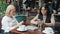 Women colleagues using smartphones touching screen during business lunch in cafe
