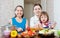 Women cook vegetables, while baby eats salad