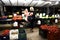 Women customer and seller standing near stand of fresh vegetables and fruits