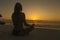 Women do meditation the ocean beach at sunset