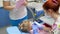 Women doctor in medical mask using tools for cures teeth of little patient and beside assistant