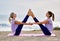 Women doing yoga exercise wide legged boat pose near the sea