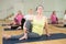 Women exercising during yoga class in fitness center - marichiasana pose