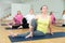 Women exercising during yoga class in fitness center - marichiasana pose