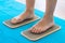 Women feet are standing on a board with sharp nails, Sadhu Board. yoga practice. pain, trial, health. blue yoga mat.