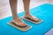 Women feet are standing on a board with sharp nails, Sadhu Board. yoga practice. pain, trial, health. blue yoga mat.