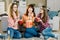 Women friendship, home party. Three beautiful funny young girl friends with popcorn in hands sitting on the floor in