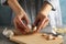 Women with garlic bulbs in her hands, bowl of garlic slices, board on wooden background. Closeup