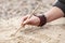 Women Hand with bracelets writing on sand with wooden stick