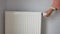 women hand changing temperature on heating radiator