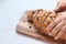 Women hand cutting baked brow bread on table.