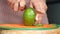 women hand cutting slice of avocado with knife,