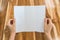 Women hand hold Trifold white template paper on wood texture .