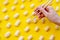 Women hand holding corn sticks on wooden chopsticks. Sweet corn sticks on yellow background