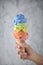 Women hand holding Rainbow ice cream cone on marble background