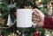 Women hand holding white ceramic coffee cup on christmas tree background. mockup for creative advertising text message or