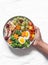 Women hand with a large snack plate. Boiled egg, broccoli, carrots, apples with peanut butter, grapes - delicious diet breakfast,