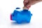 Women hand putting coin into a piggy bank over gray background