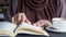 women hand reading a book at library