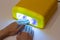 Women hand on UV light lamp on manicure process