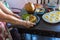 Women hands holding forks and spoons and picking spicy Thai food dinner on wooden table