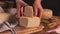 Women hands put pieces of  fresh homemade cheese on a wooden board close up