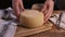 Women hands showing fresh homemade cheese on a wooden board with a cheese knife close up