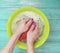 Women hands are washed in a basin on a blue on a wooden background