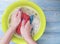 Women hands are washed holding bubble home foam service in a basin on a blue on a wooden background