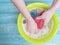 Women hands are washed holding home foam service in a basin on a blue on a wooden background