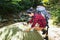 Women hiker with backpack checks map to find directions in wilderness area at waterfalls and forest.