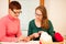 Women knitting with red wool. Eldery woman transfering her knowledge of knitting on a younger woman on handcraft workshop.