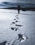 Women leaves deep foot prints while walking on frozen snowy lake