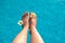 women legs pedicure nails splashing in tropical swimming summer pool