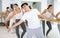 Women and men training in ballet class with other dancers in studio