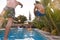 Women Outdoors Relaxing At Summer Pool Party Watching Men Dive Into Water