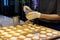 Women pastry chef are taking a pastry brush and brushing egg wash on top of cheese tart in the kitchen at the bakery shop