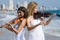 Women play violin on beach