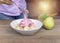 Women pour  yogurt strawberry from spoon to bowl and in bowl have banana slide , guava oat on wood table