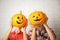 Women with pumpkin heads near brick wall. Jack lantern - traditional Halloween decor