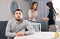 Women quarrel while sad man sits at table at home
