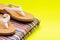 Women`s Causal Braided natural color Beach Day Flip Flops and folded colorful striped beach towels on bright yellow